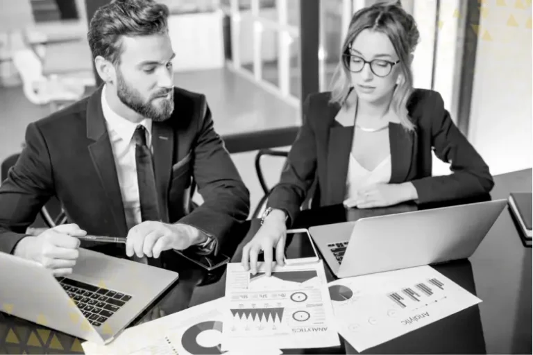 Two business professionals sit at a desk and import audience data from Google Analytics 4 into Google Ads