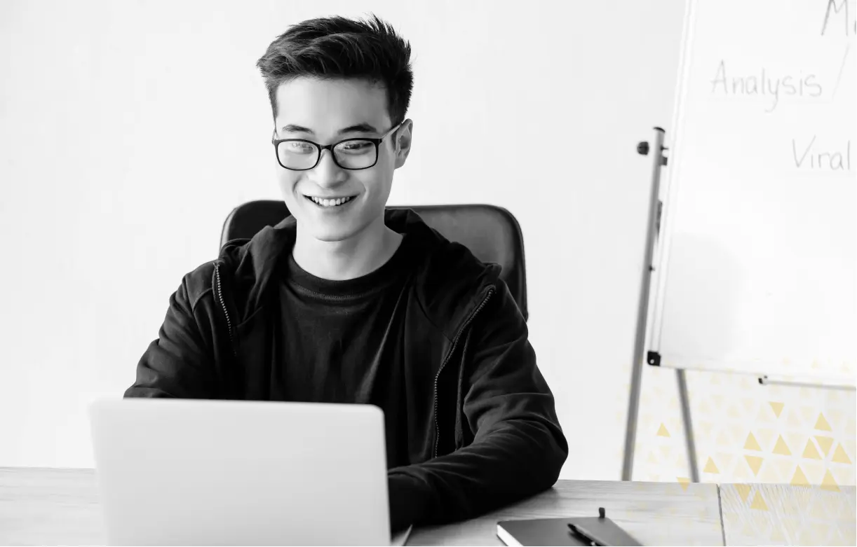 man smiling on laptop sitting at desk